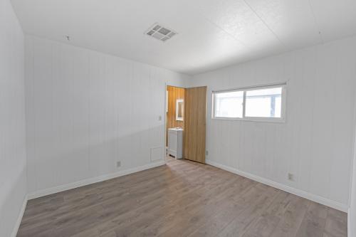 An empty room with wood floors and a washer and dryer.