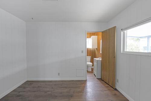 An empty room with wood floors and a toilet.