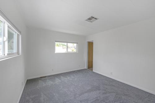 An empty room with gray carpet and a window.