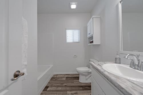A white bathroom with wood floors and a sink.