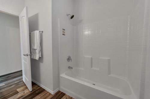 A white bathroom with wood floors and a tub.