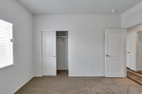 An empty room with white walls and a closet.