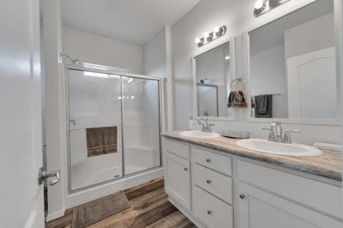 A white bathroom with wood floors and a walk in shower.