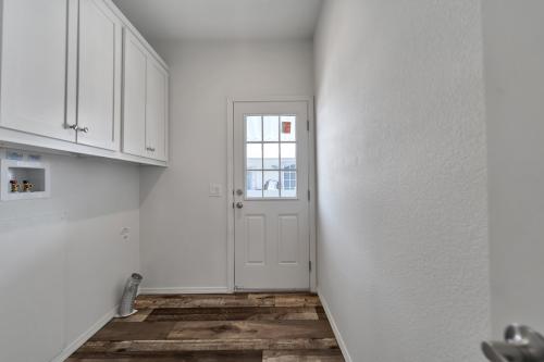 A hallway with wood floors and white cabinets.