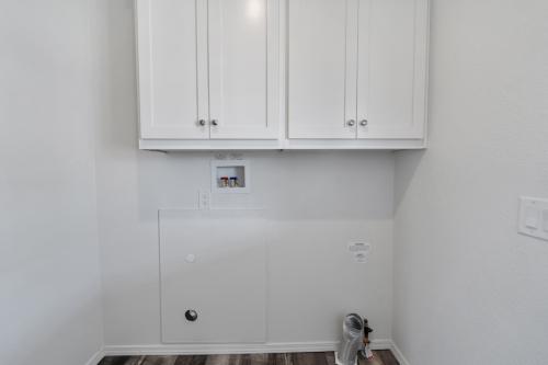 A small room with white cabinets and hardwood floors.